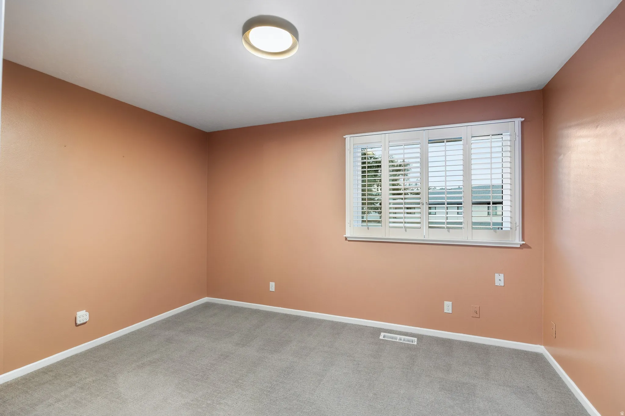Interior room featuring light peach-toned walls and gray carpeting