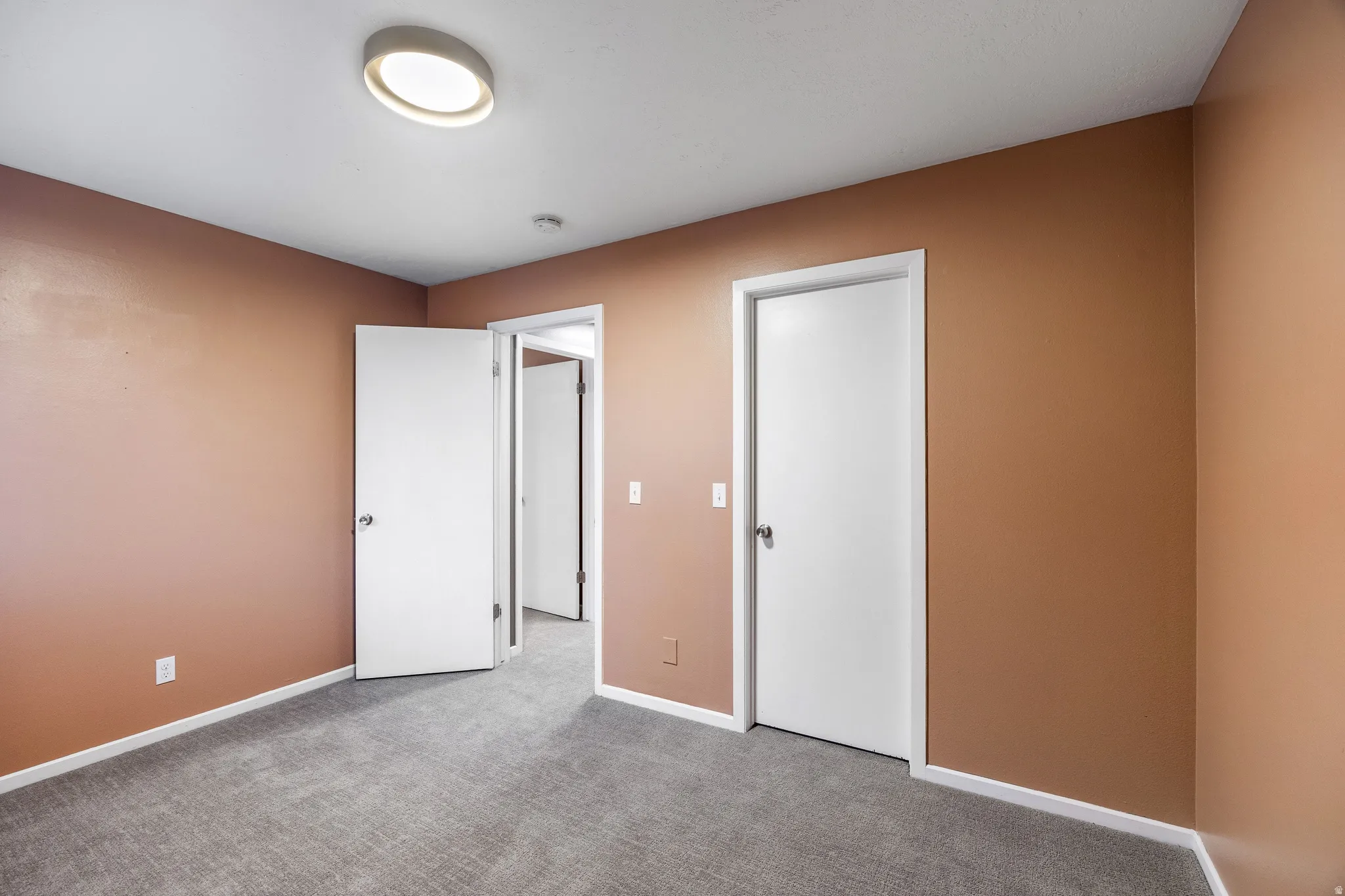 Interior room featuring light brown walls and neutral gray carpeting