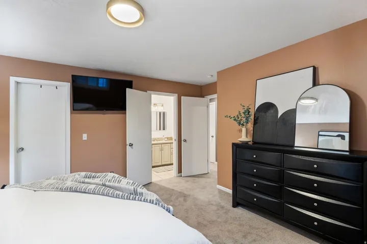 Carpeted room featuring a ceiling-mounted light fixture and a wall-mounted television