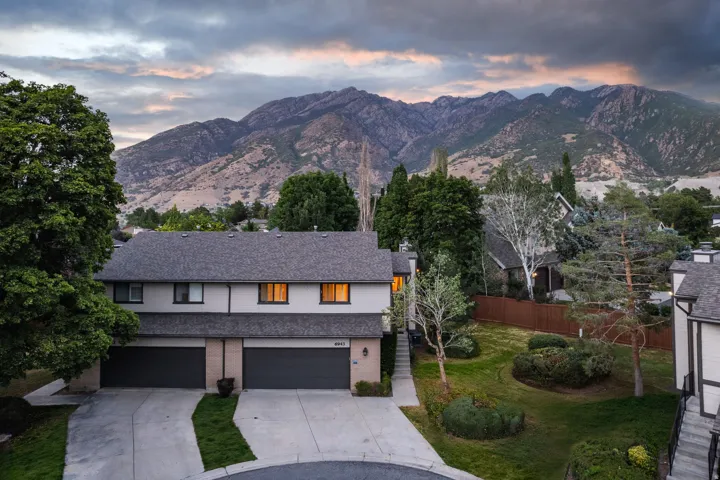 Mountain backdrop framing a multi-unit property with a dark gray shingled roof