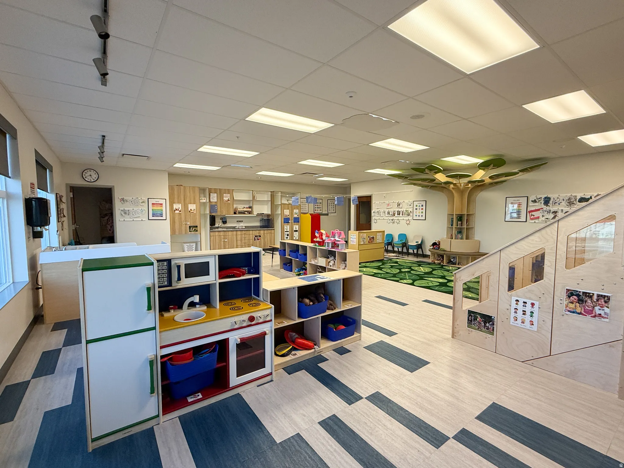Spacious room featuring patterned flooring, recessed and track lighting, built-in cabinetry with a sink, and multiple windows