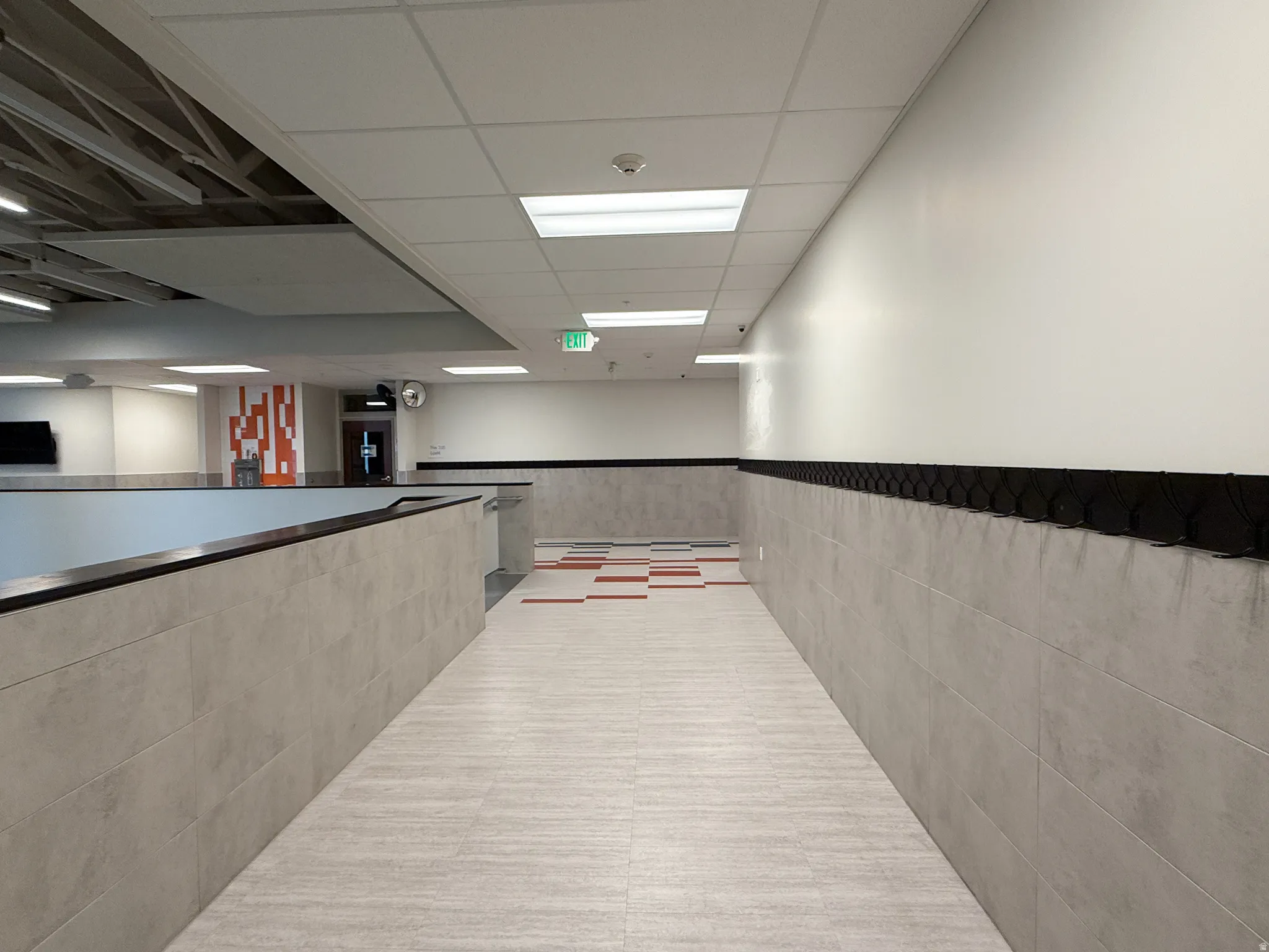 Hallway featuring light-toned tile flooring and gray wainscoting