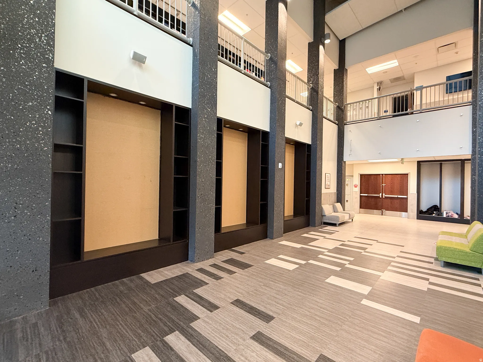Spacious multi-level interior featuring high ceilings, contemporary patterned flooring, and built-in wall shelving