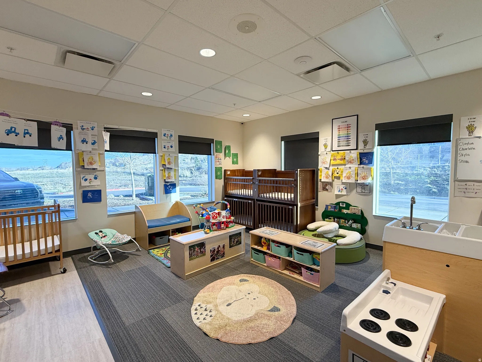 Spacious interior room featuring a combination of wood-finish flooring and carpet tiles