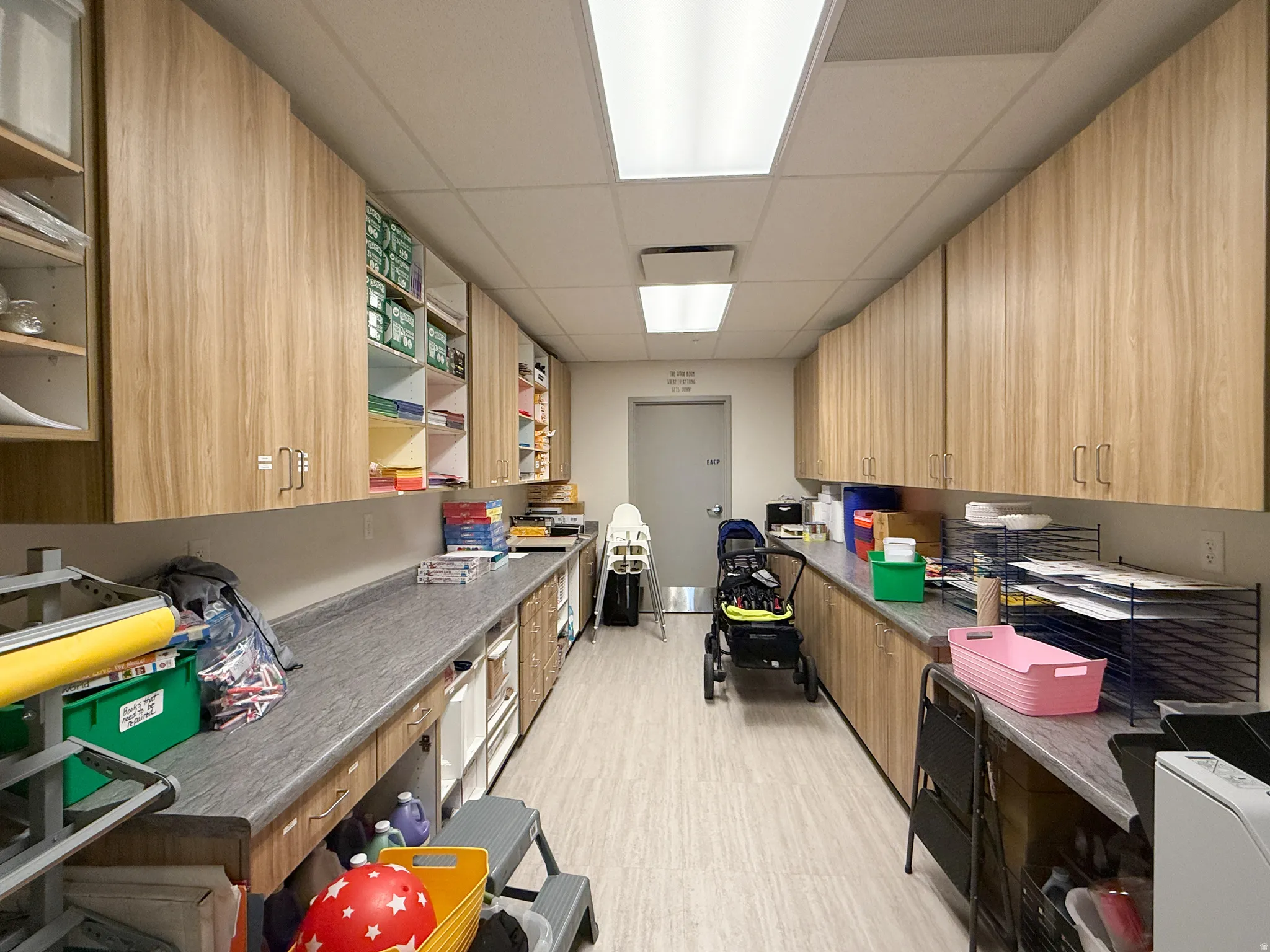 Spacious room featuring extensive wood-finish cabinetry, gray countertops, and light-colored flooring