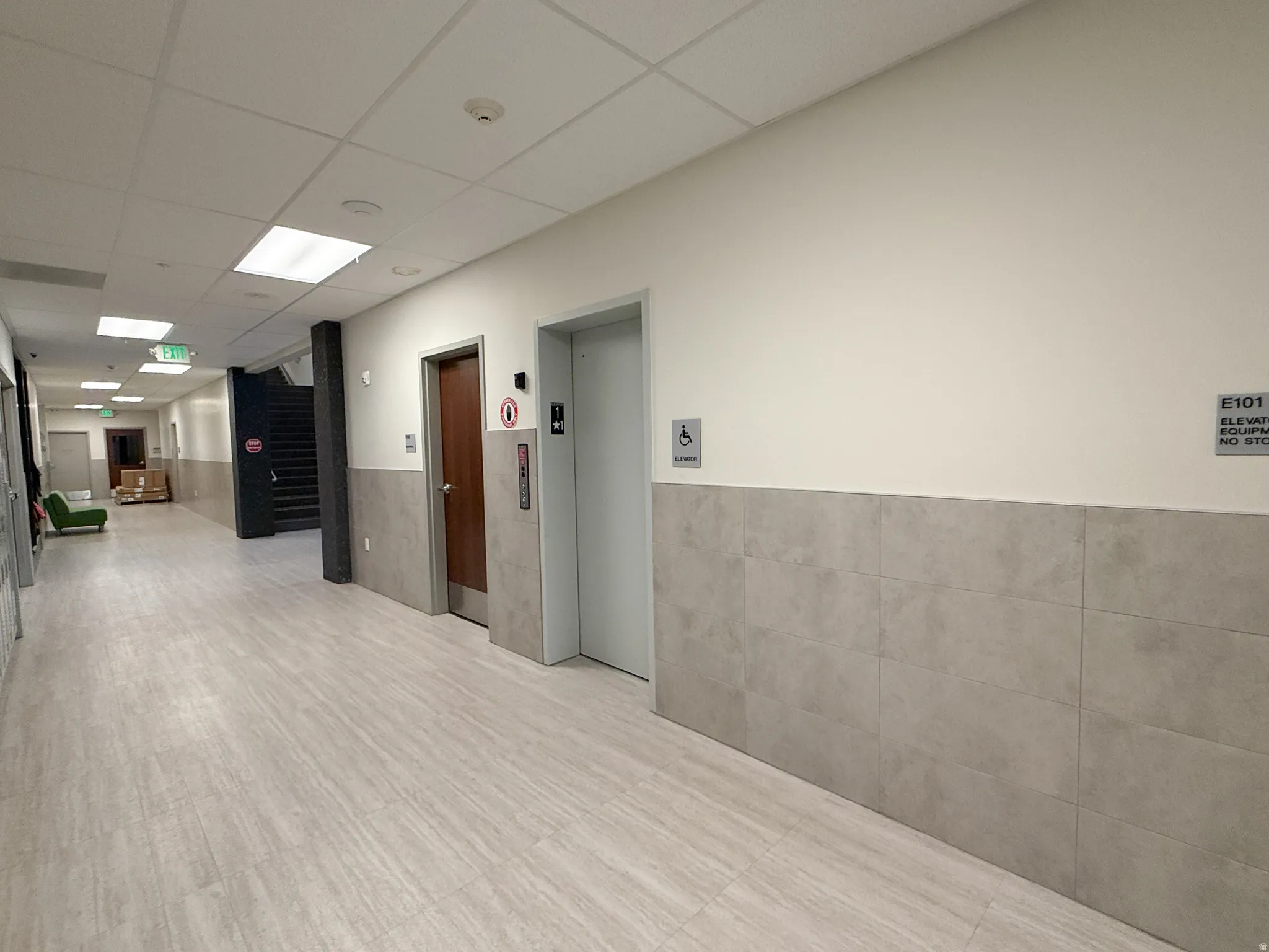 Corridor featuring light wood-finish flooring and a tiled wainscot