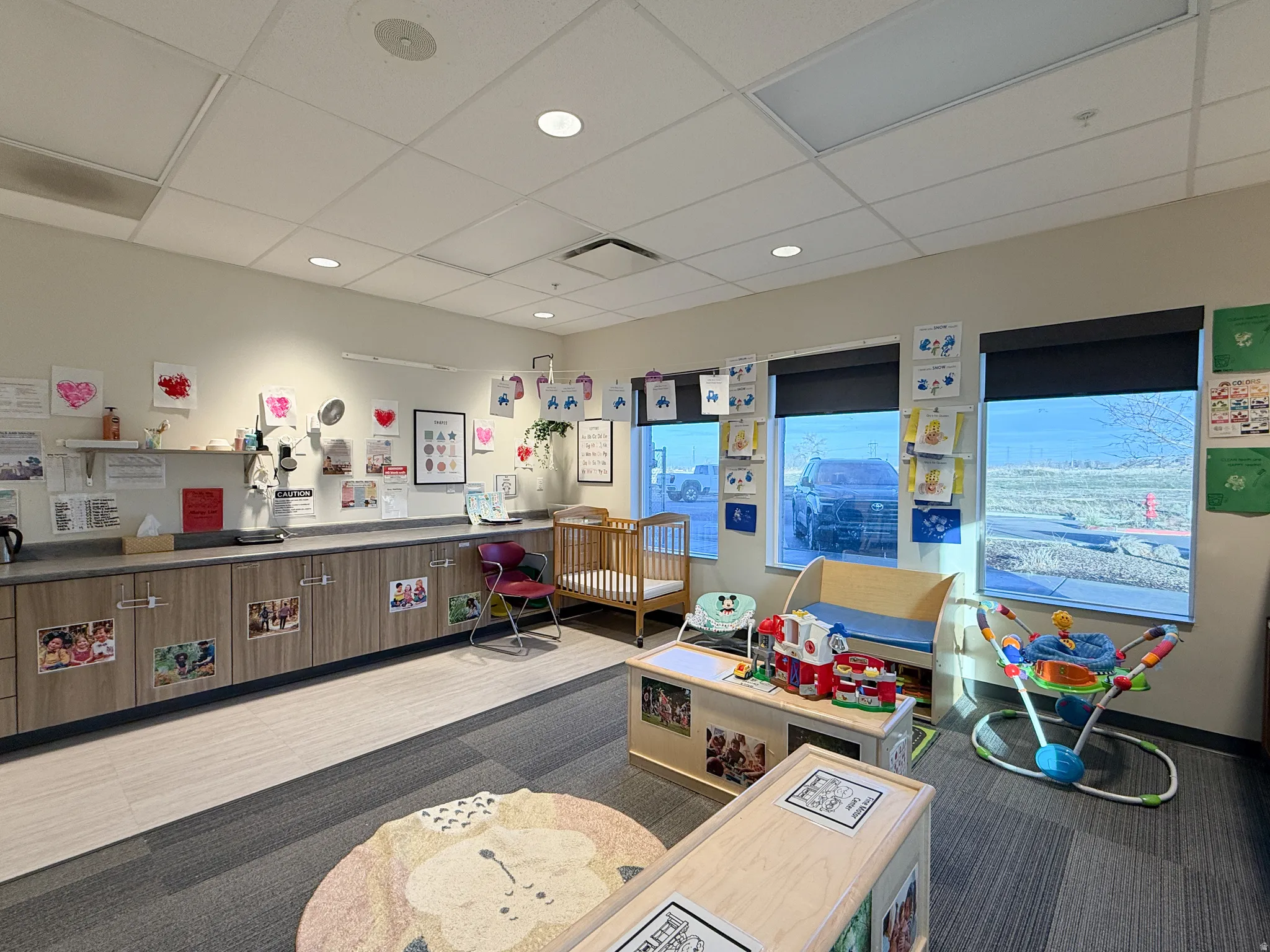 Interior space featuring a long countertop with base cabinetry, multiple windows with roller shades, recessed lighting, and a suspended ceiling