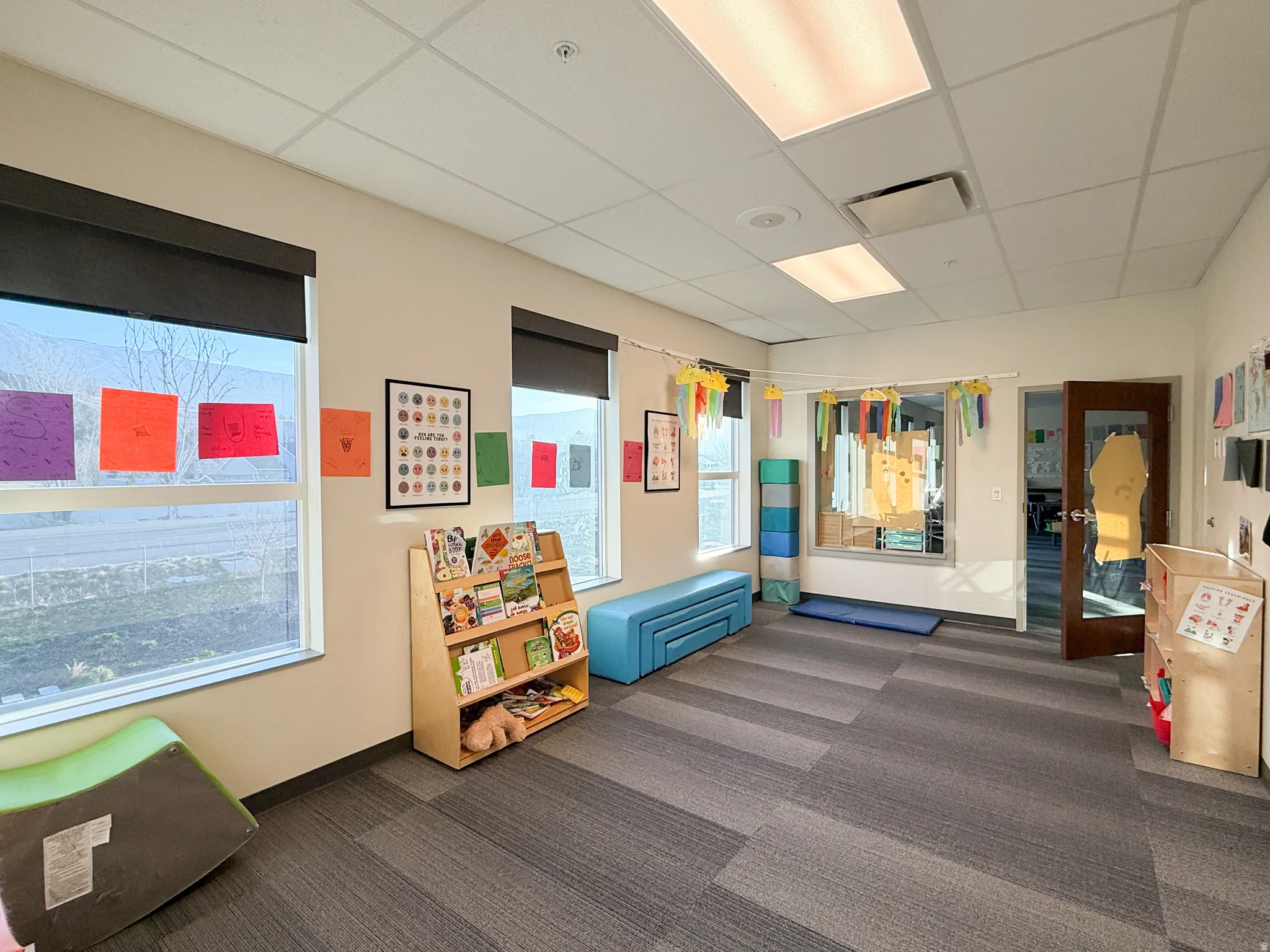 Room featuring multiple windows with roller shades, recessed lighting, and acoustic tile ceiling