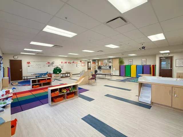 Spacious room featuring light-toned flooring with dark accent strips, drop ceiling with integrated lighting, and multiple wall-mounted whiteboards