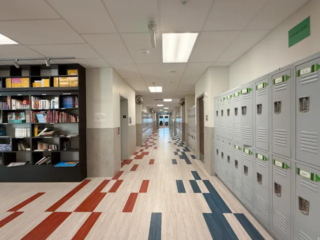 Corridor featuring patterned flooring, built-in shelving, recessed and overhead lighting, and extensive wall lockers