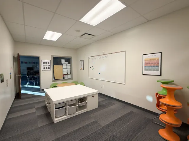 Bright room featuring modular gray carpet tiles and a white drop ceiling with recessed lighting