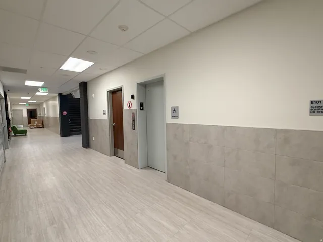 Corridor featuring light wood-finish flooring and a tiled wainscot