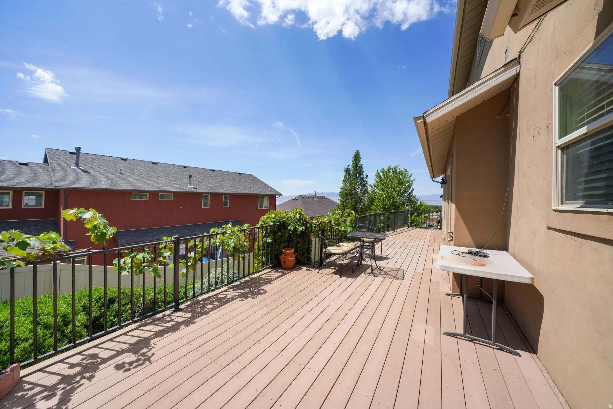 Spacious outdoor deck with composite wood-finish flooring, stucco exterior, and black metal railing