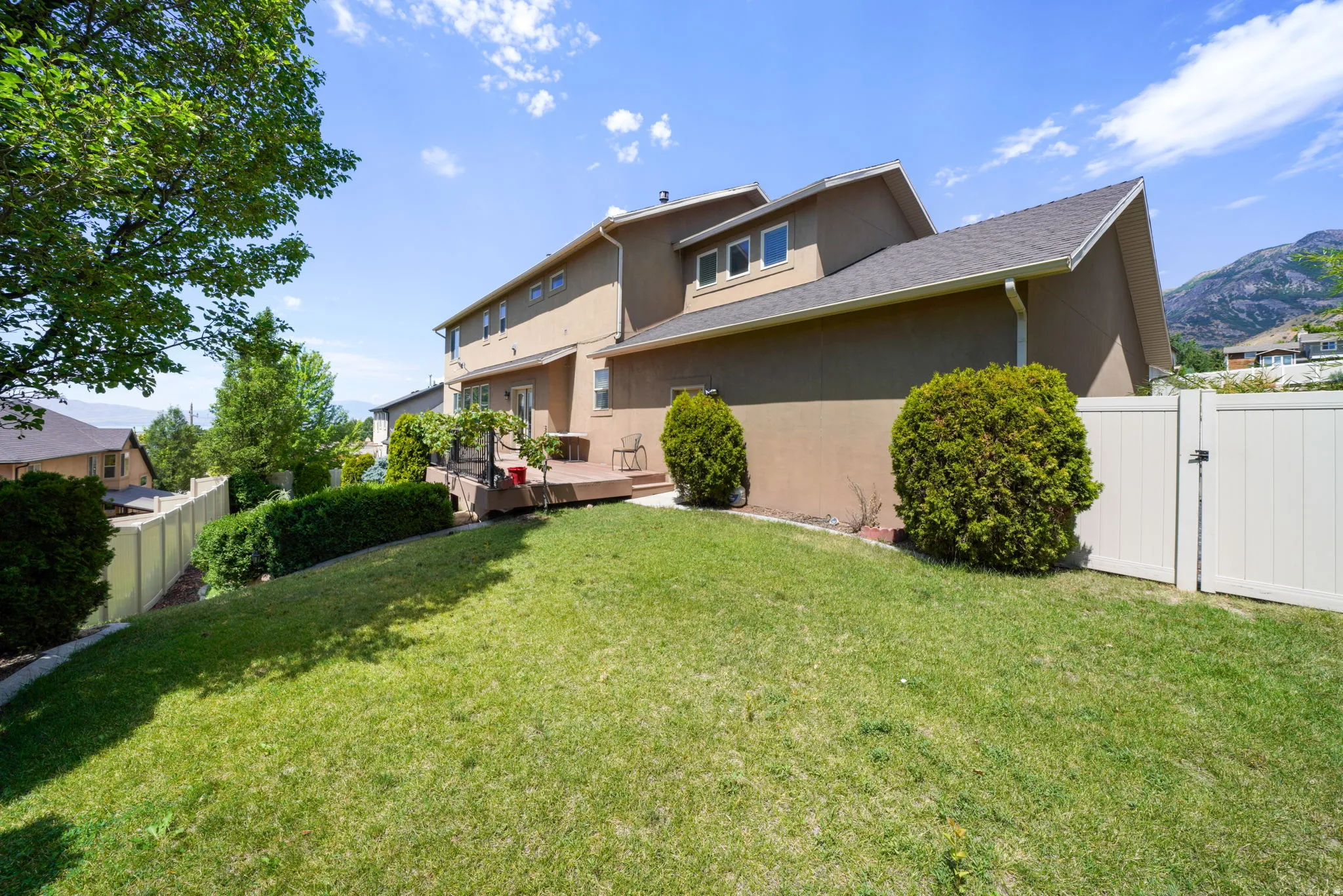 Expansive sloped lawn with mature landscaping and a private deck