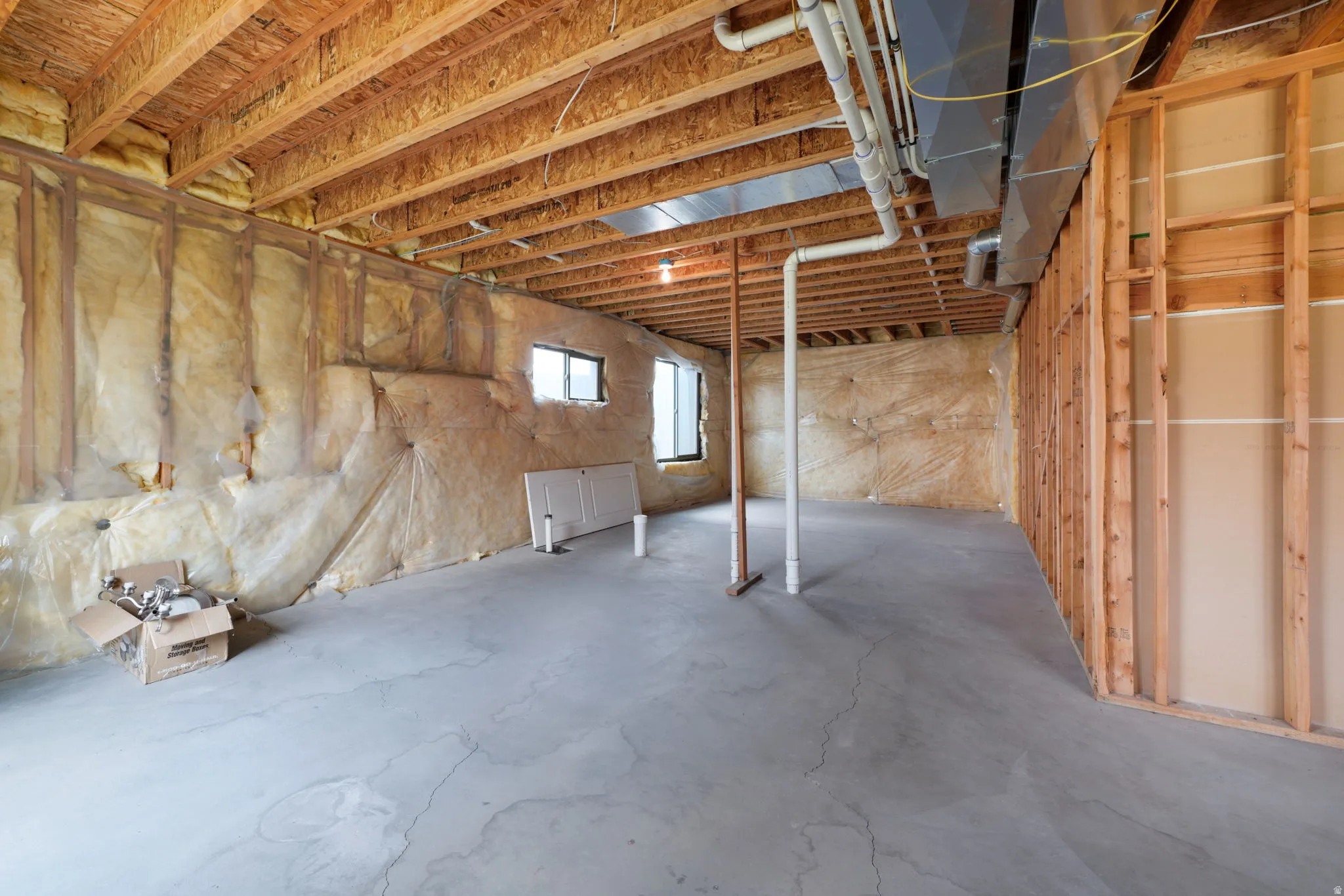 Unfinished basement featuring exposed wood joists, concrete flooring, perimeter insulation, visible framing, and multiple windows
