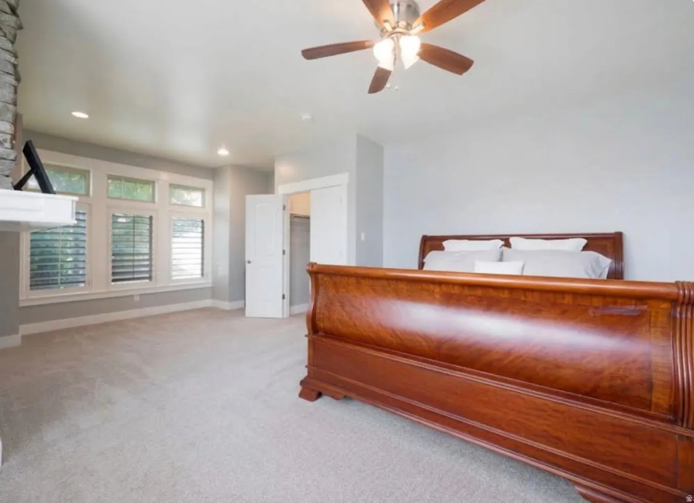 Recessed lighting, ceiling fan, carpeting, white trim, and multiple windows with horizontal blinds