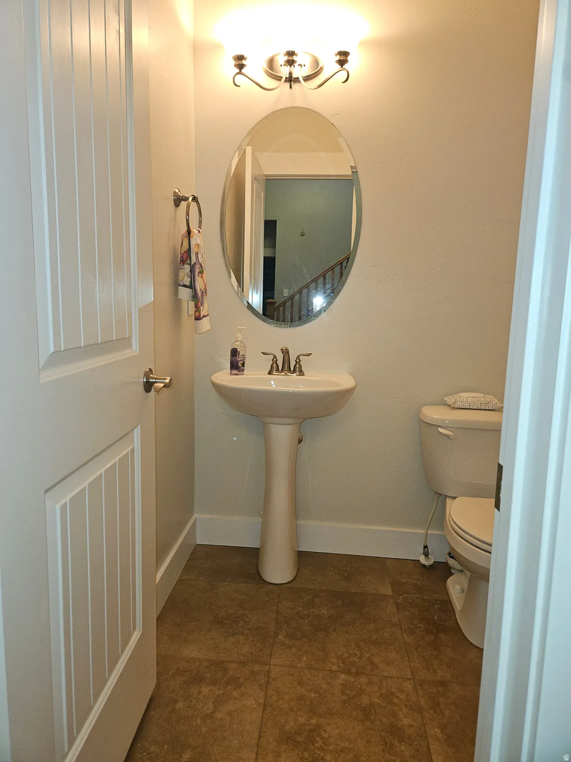 Pedestal sink and toilet in a compact bathroom featuring tiled flooring