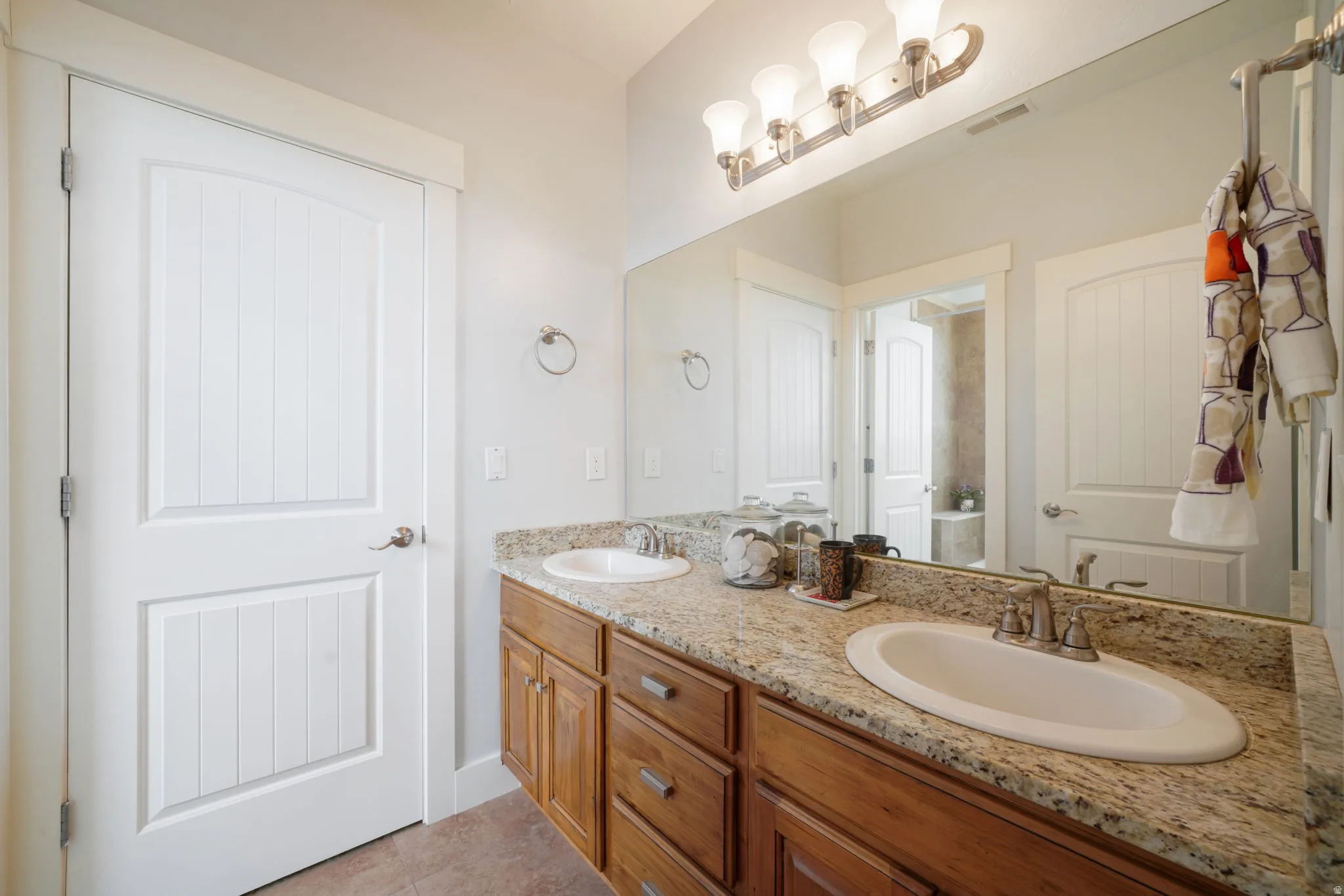 Bathroom vanity featuring dual undermount sinks, a granite countertop, and a wood-finish cabinet