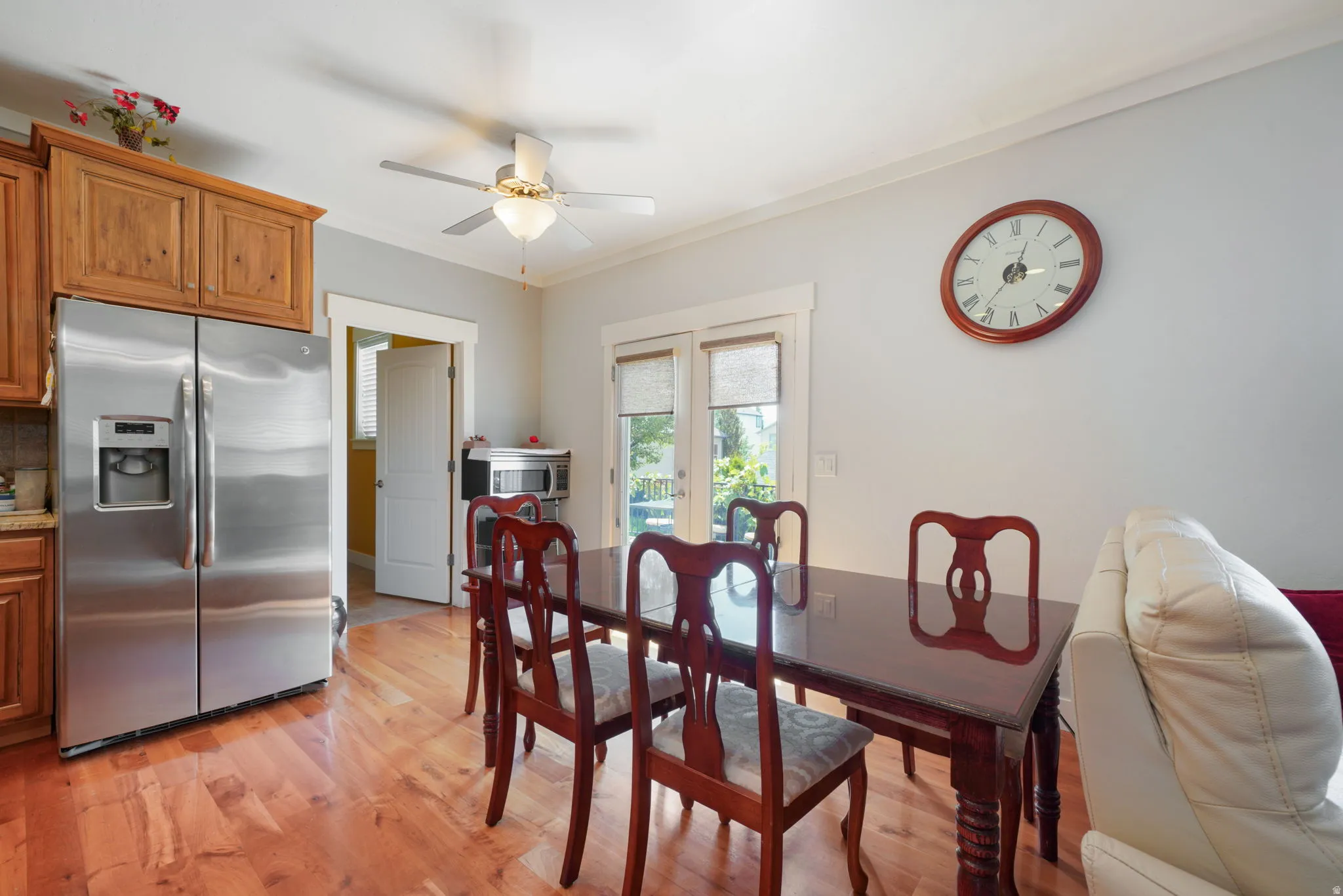 Dining area featuring wood-finish flooring, a ceiling fan with integrated lighting, and crown molding