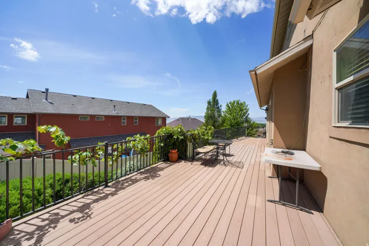 Spacious outdoor deck with composite wood-finish flooring, stucco exterior, and black metal railing