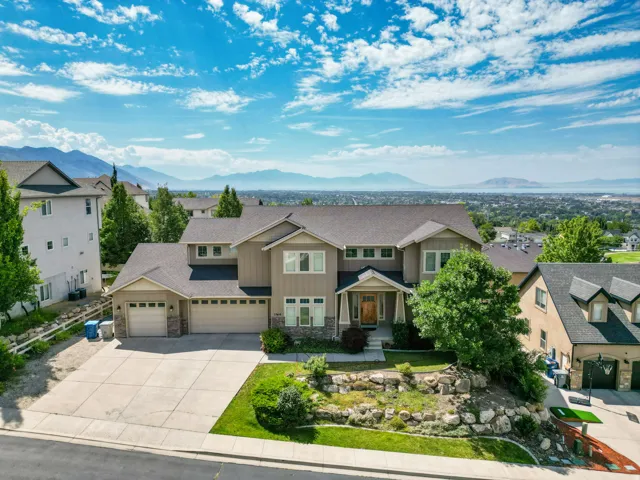 Expansive residence featuring a multi-car garage, stone and siding exterior, and a broad paved driveway