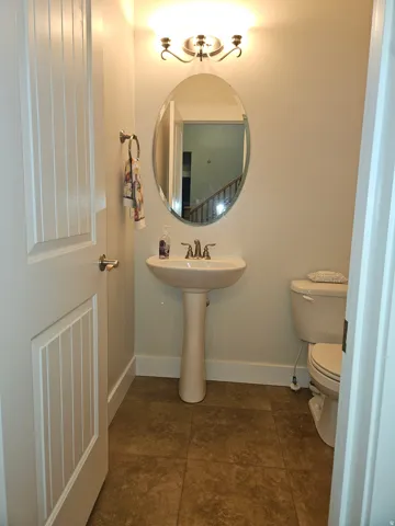 Pedestal sink and toilet in a compact bathroom featuring tiled flooring