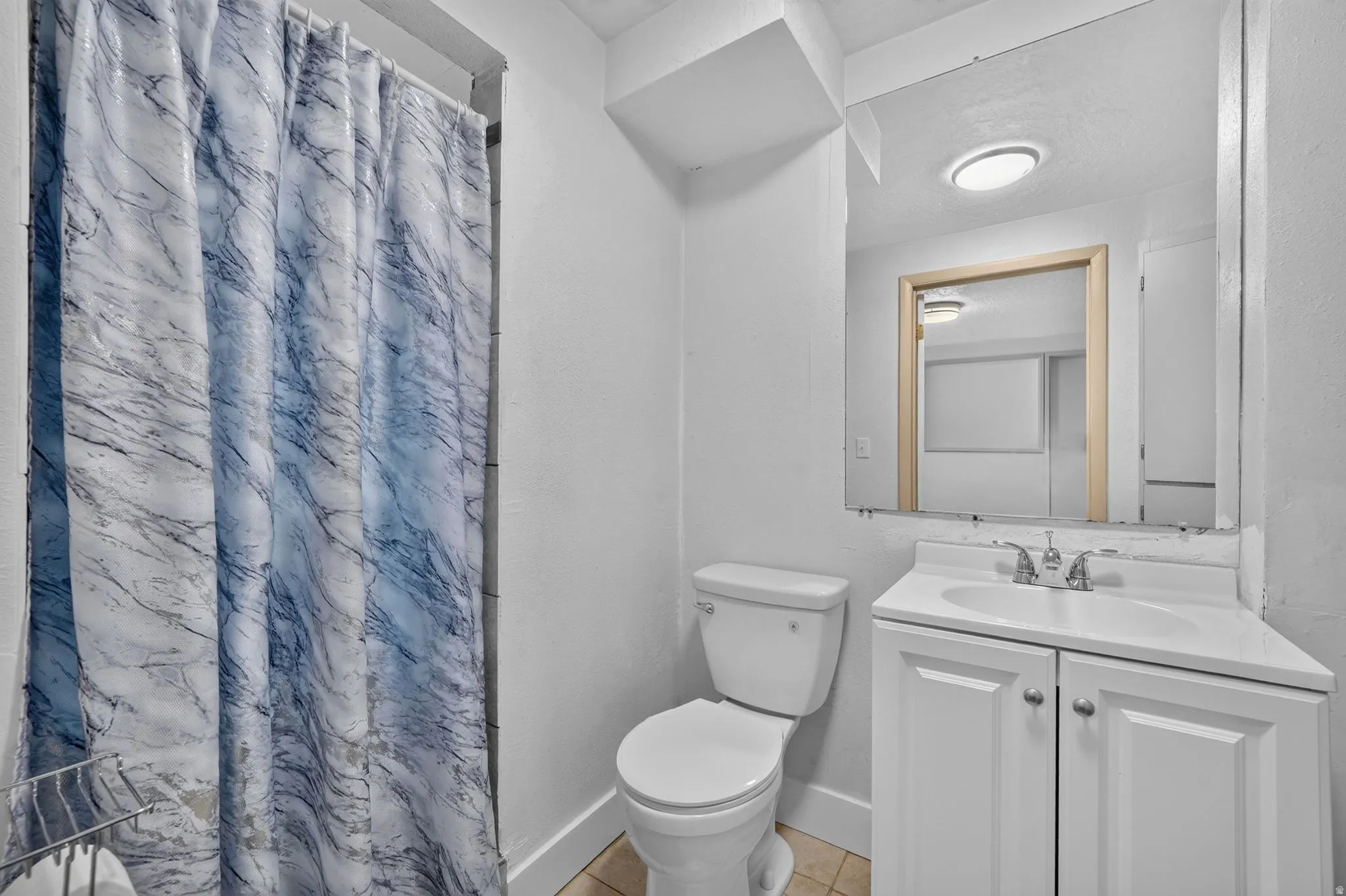 Bathroom featuring a white vanity with integrated sink, chrome-finish faucet, and a wall-mounted mirror
