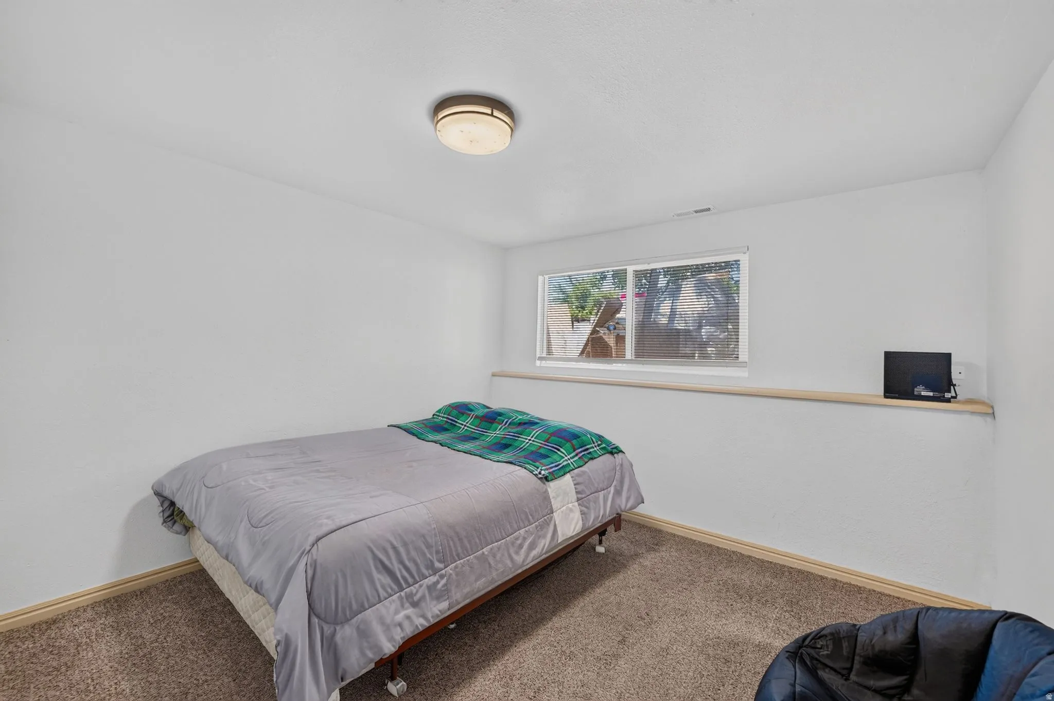 Carpeted room with a flush-mount ceiling light fixture, a window with a wood sill, and light-toned baseboards