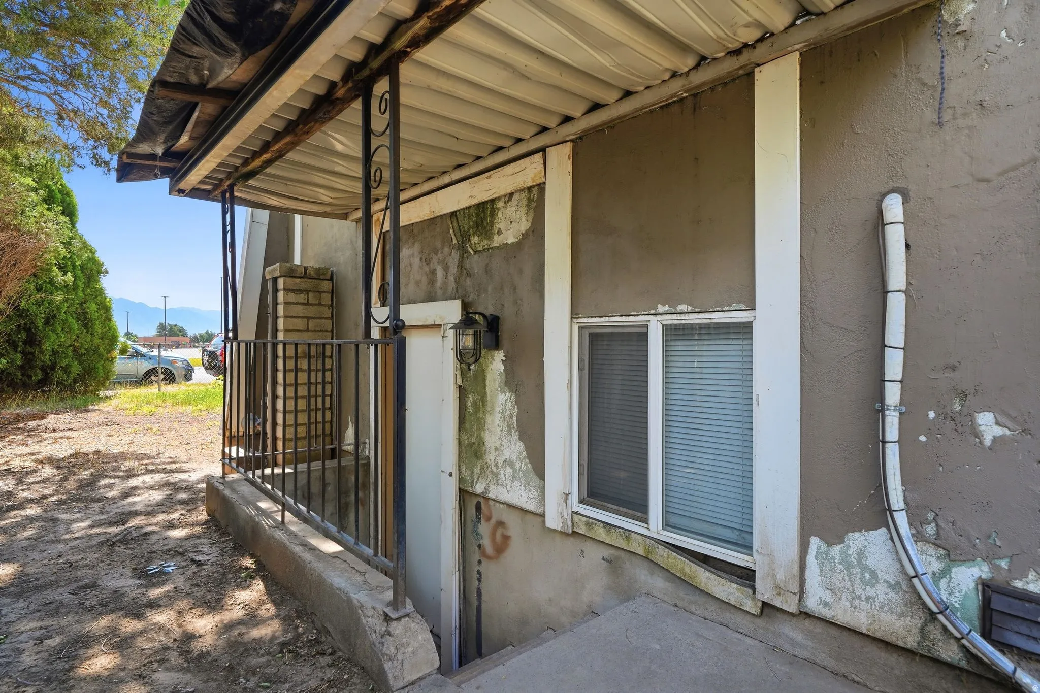 Covered entryway featuring ornate metal railing, a brick column detail, and exterior wall sconce
