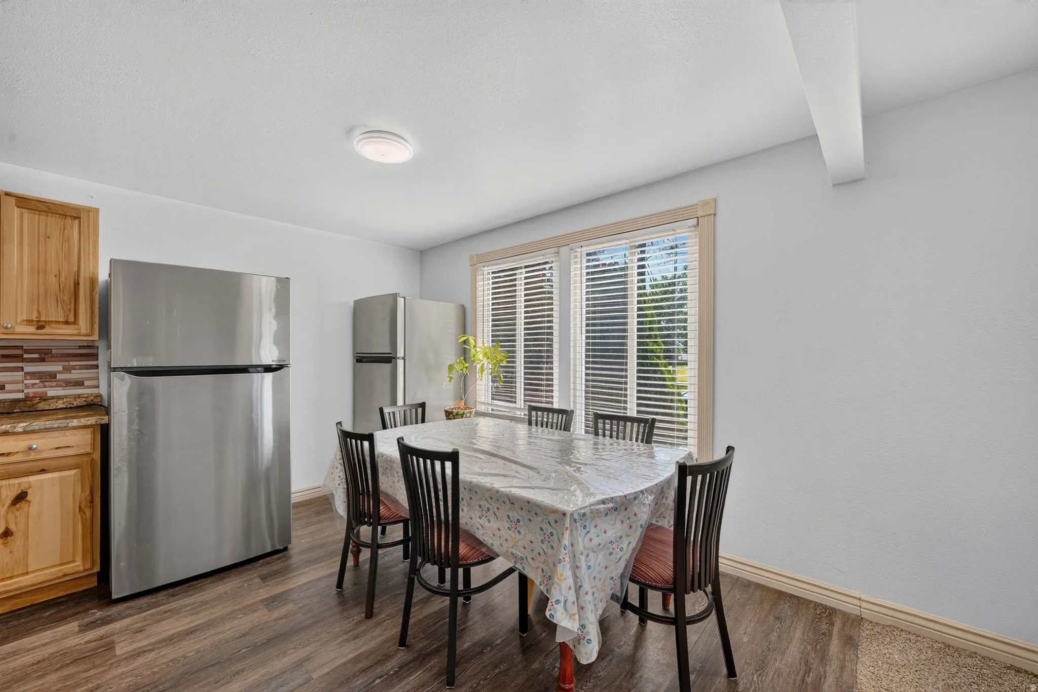 Dining area featuring wood-finish flooring and a bright window with horizontal blinds