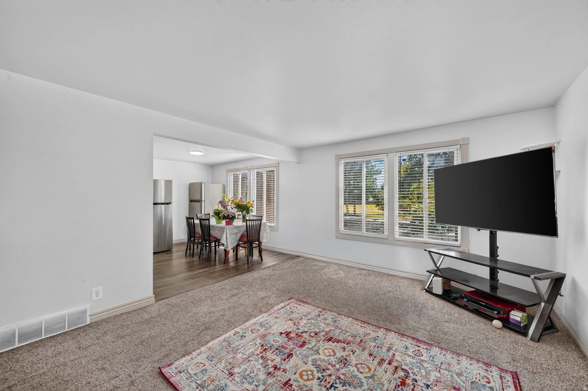 Bright living area featuring neutral carpeting and a large window with horizontal blinds