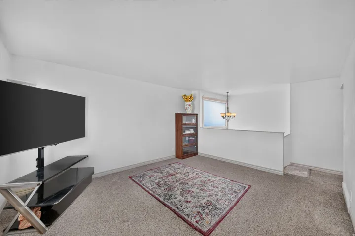 Carpeted room featuring a half-wall with a window and a multi-bulb chandelier