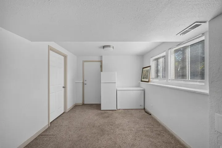 Carpeted room with white walls, two paneled doors, and two windows featuring horizontal blinds