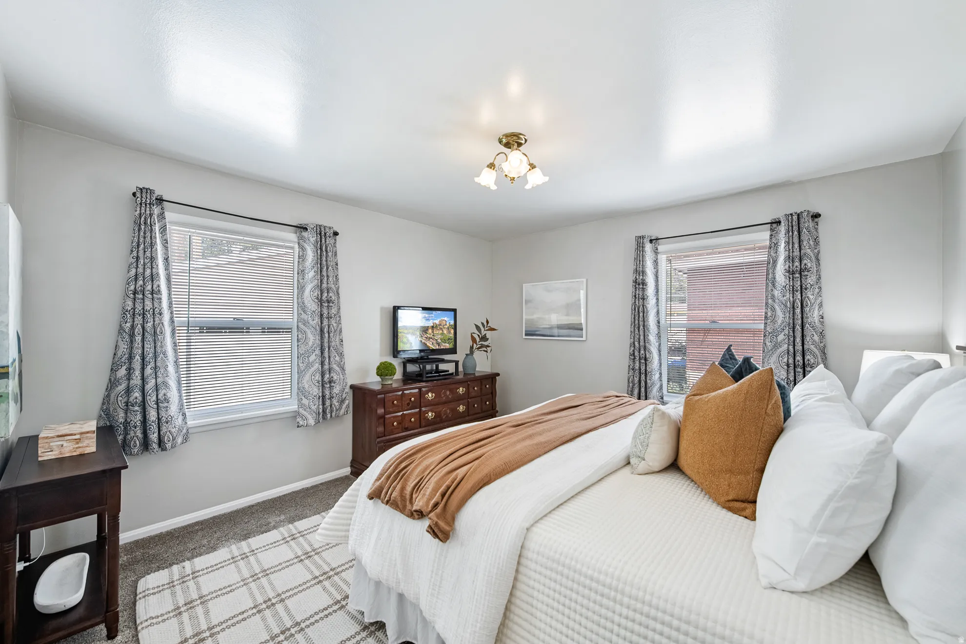 Neutral wall paint, carpeted flooring, two windows with blinds, and a built-in ceiling light fixture