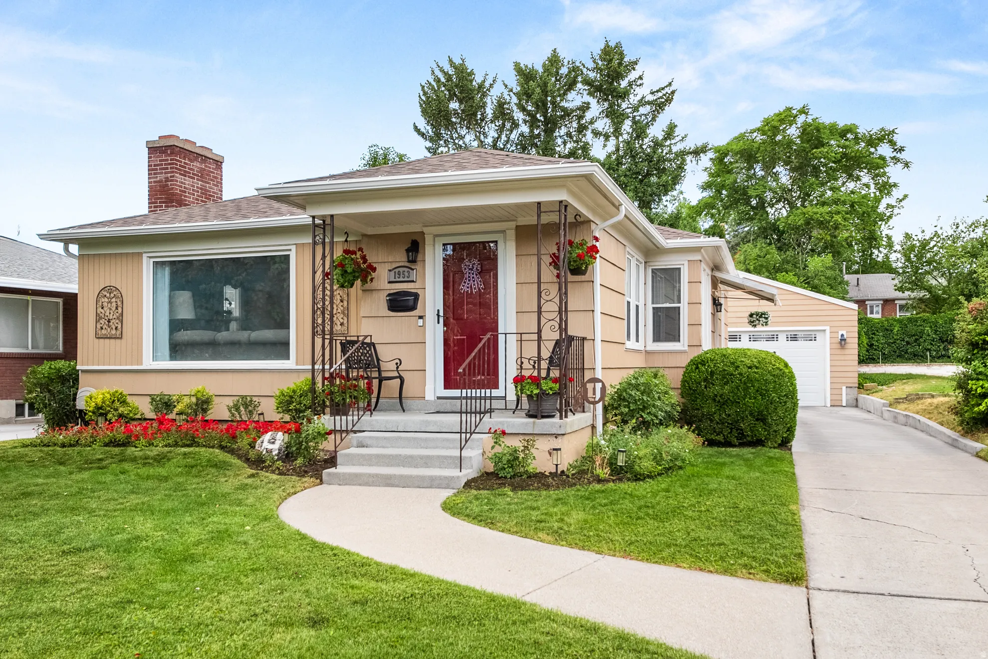 Front exterior showcasing a covered porch with decorative railing, a red entry door, and light-toned siding