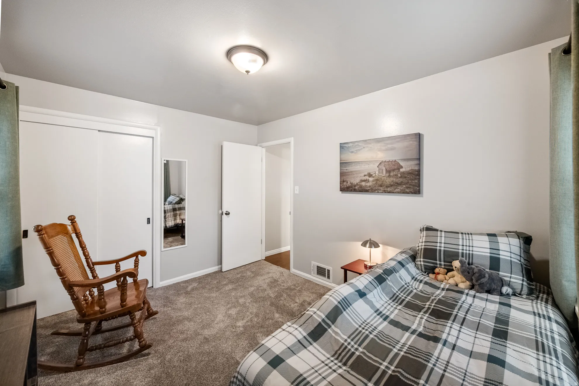 Carpeted room with light gray walls, featuring a sliding door closet with white panels