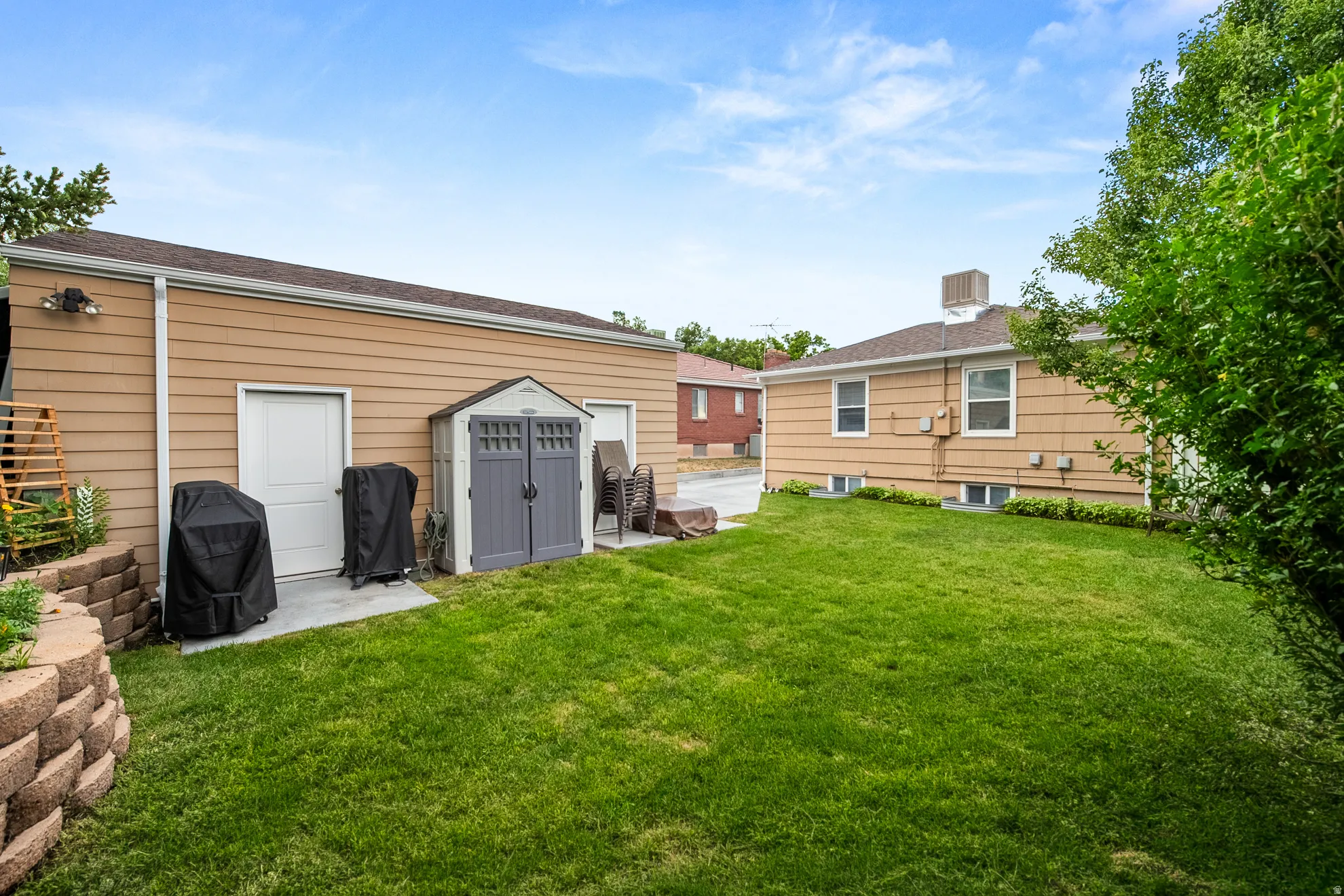 Expansive green lawn with a retaining wall, offering a spacious outdoor area