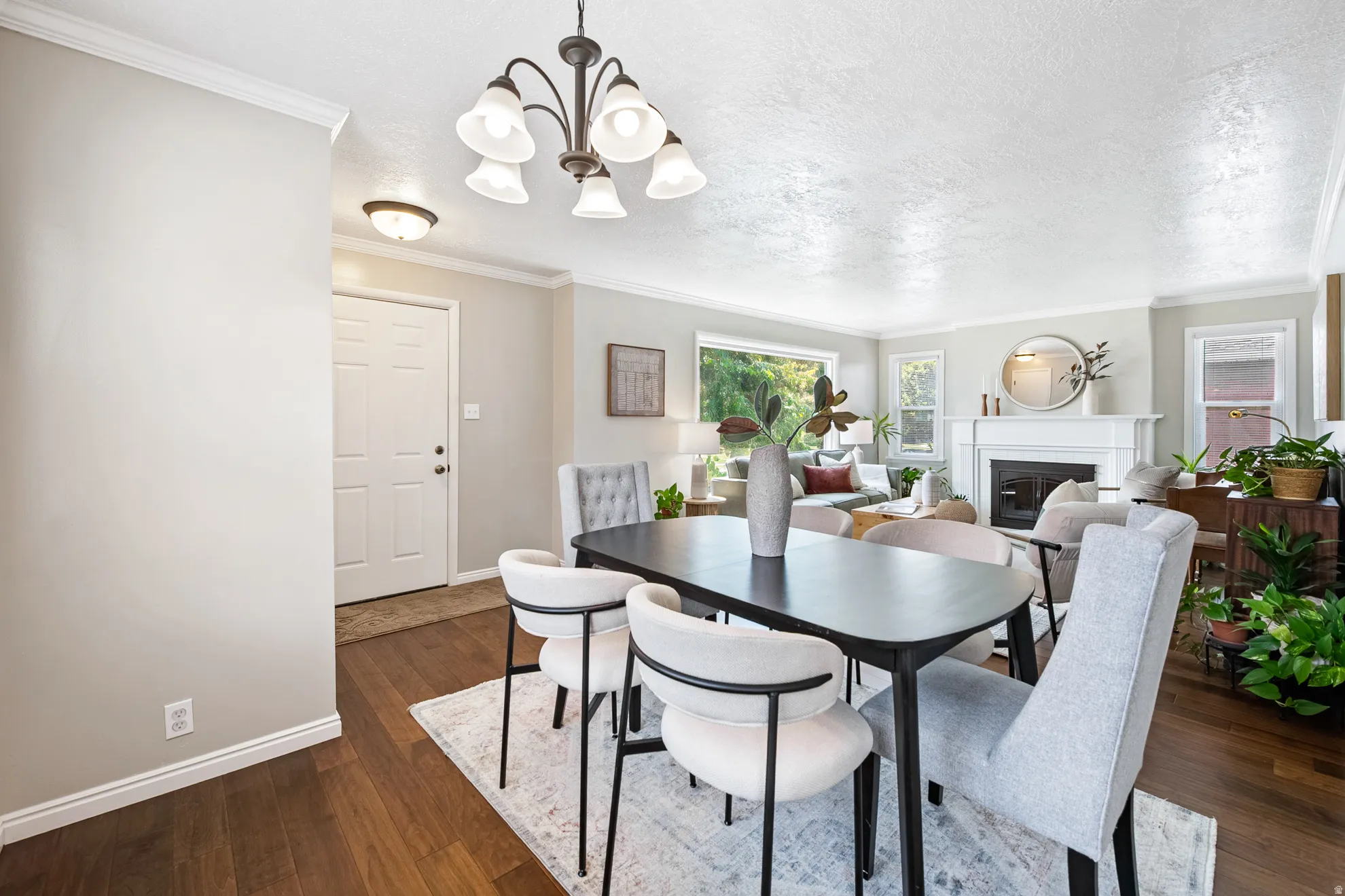Hardwood-finish flooring, crown molding, built-in fireplace, paneled interior door, and a multi-light chandelier