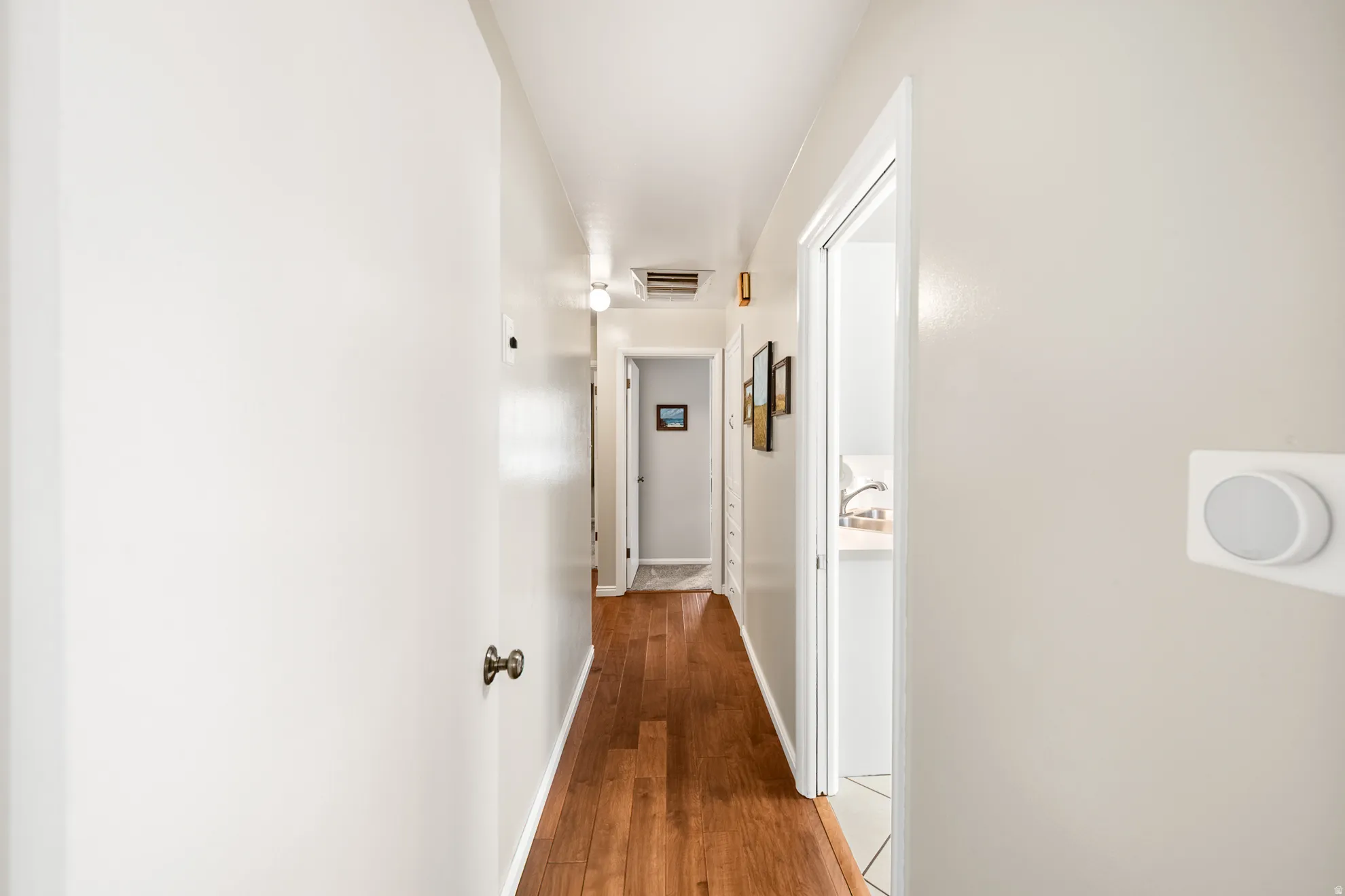 Hallway featuring warm wood-finish flooring and neutral wall tones