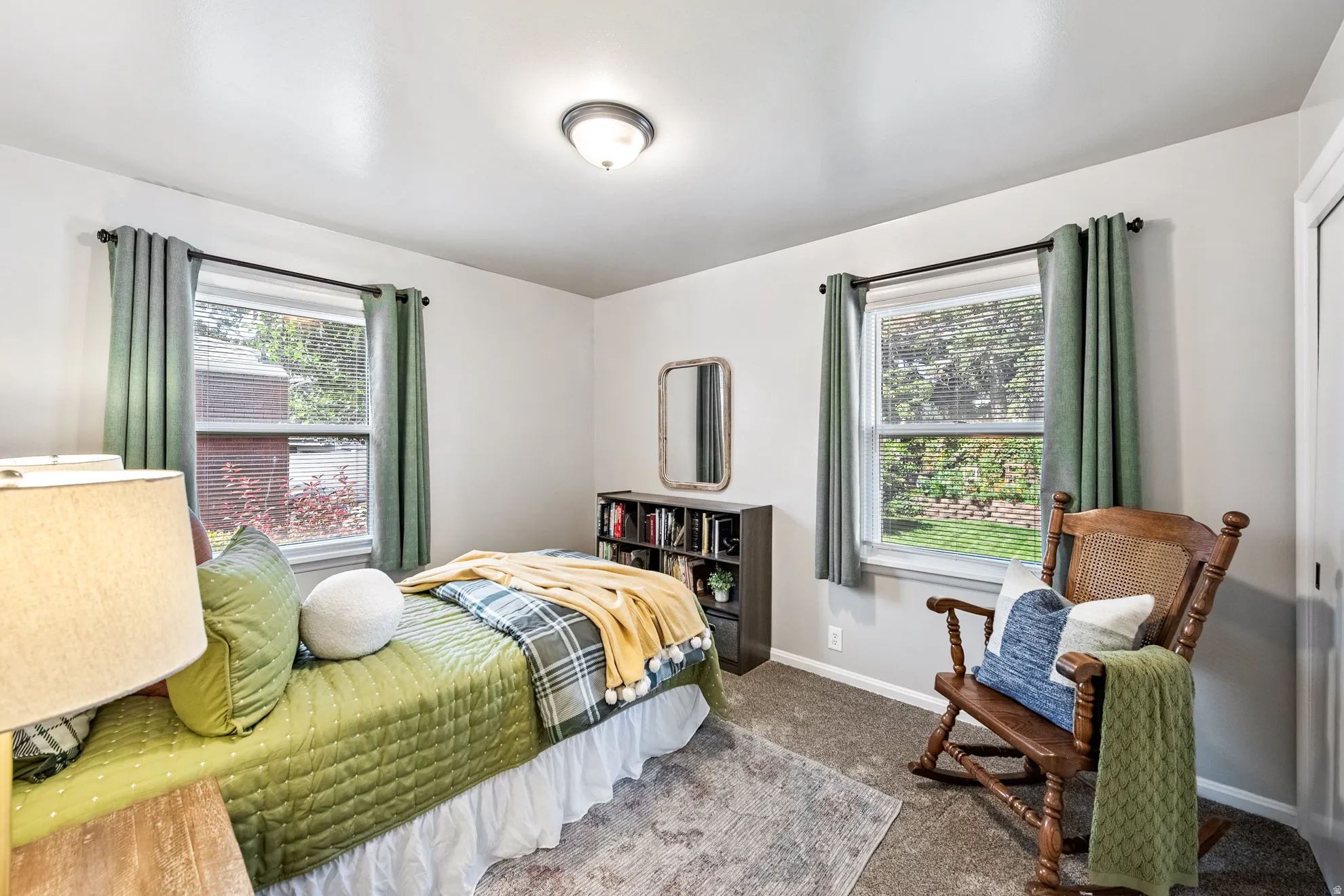 Neutral wall paint, two windows, ceiling-mounted light fixture, and carpeted flooring