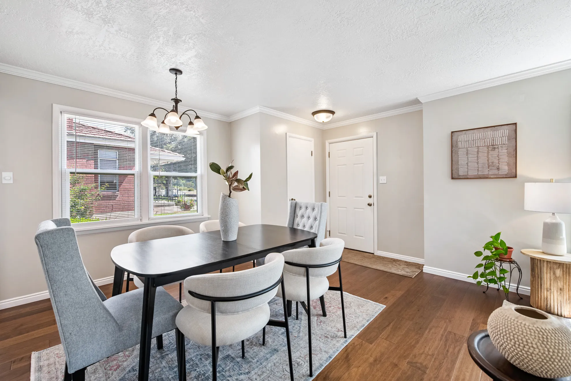 Hardwood flooring, crown molding, white trim, a multi-pane window, and a ceiling-mounted light fixture