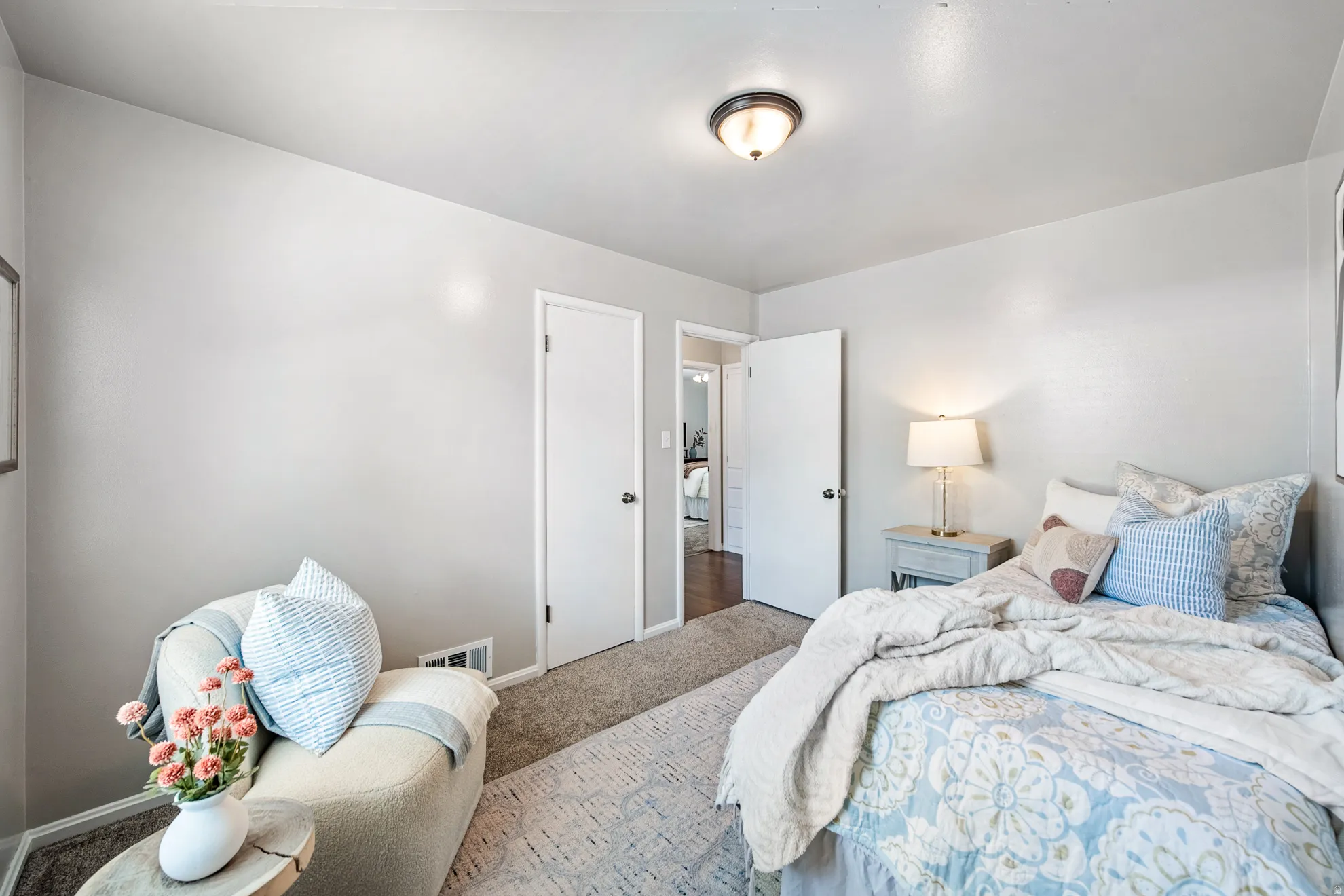 Wall-to-wall carpeting with an area rug, white interior doors, and a ceiling-mounted light fixture
