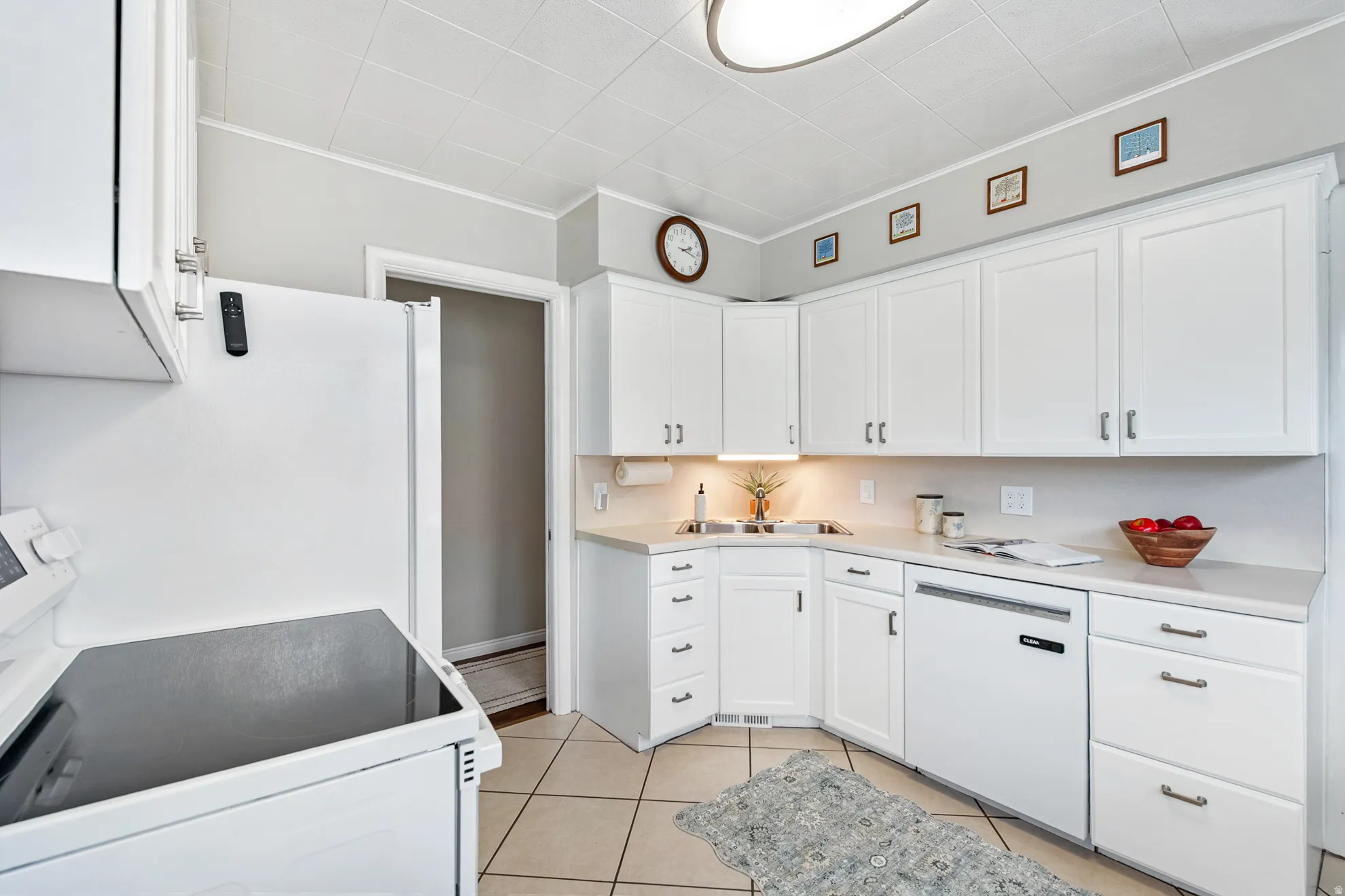 White cabinetry, light-toned countertops, tile flooring, and integrated white appliances