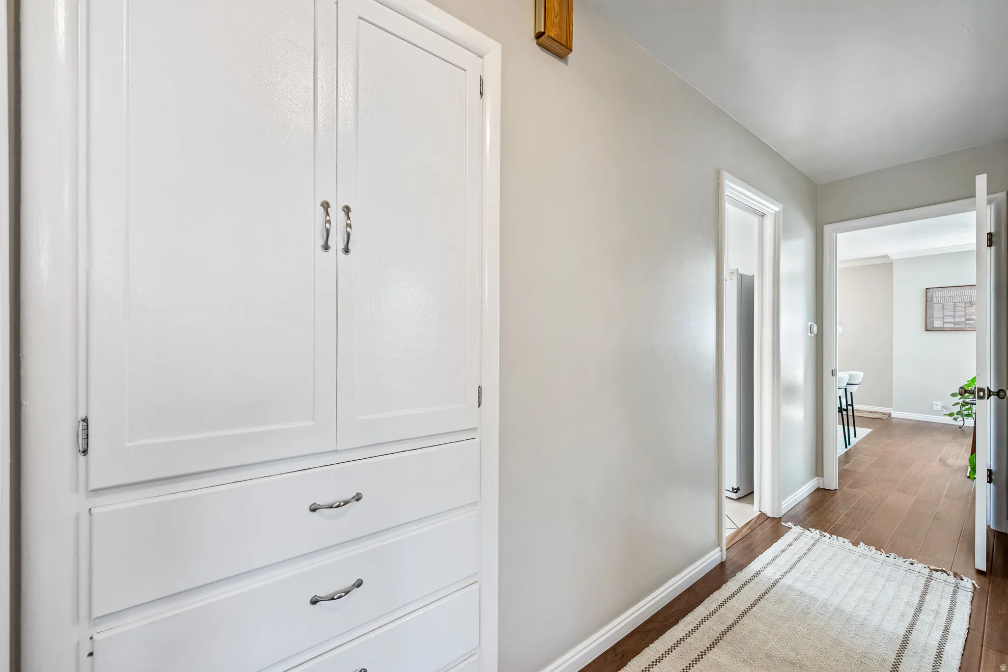White built-in cabinetry with silver-tone hardware, light gray wall paint, and wood-finish flooring
