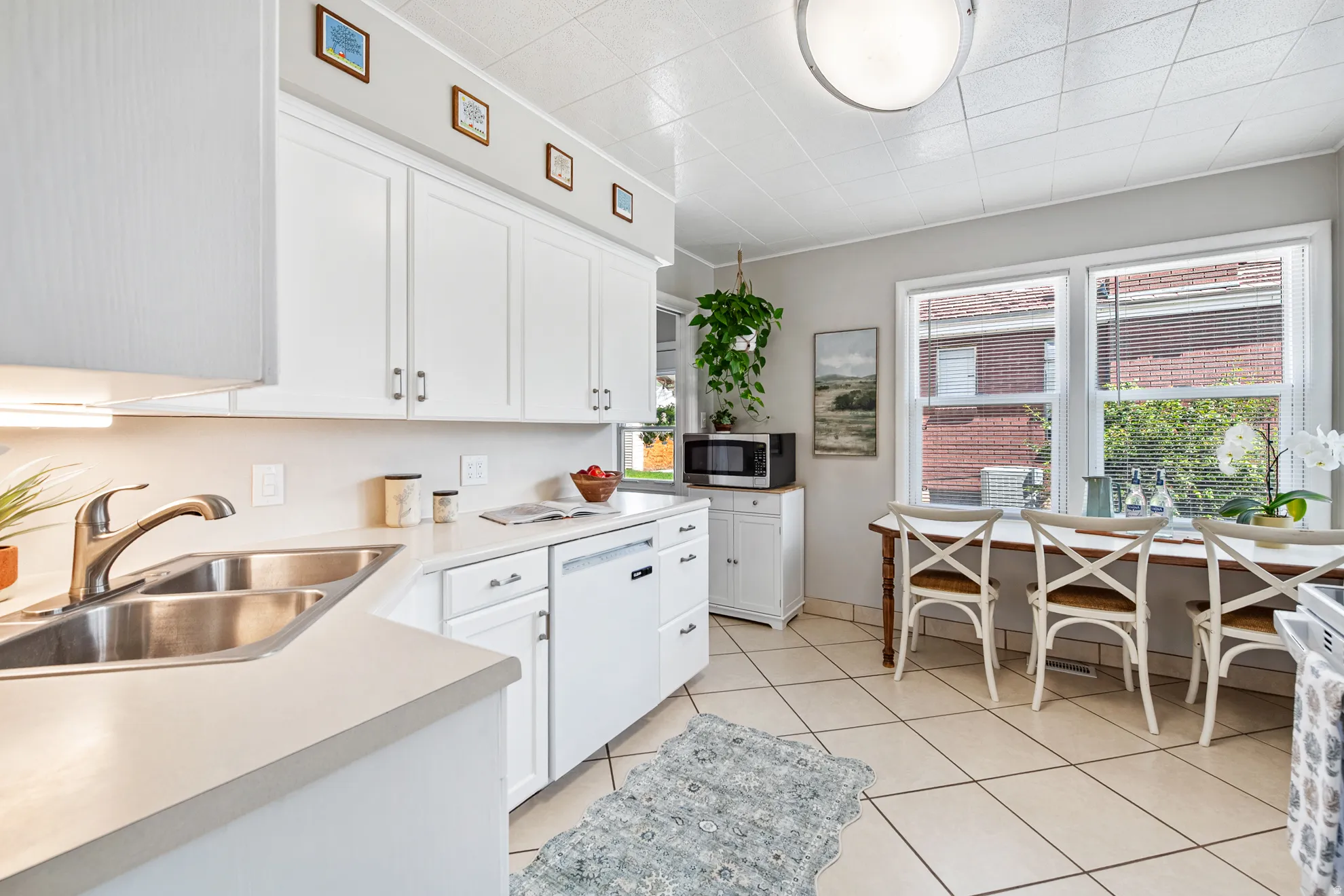 White cabinetry, solid surface countertops, dual basin stainless steel sink, and tile flooring