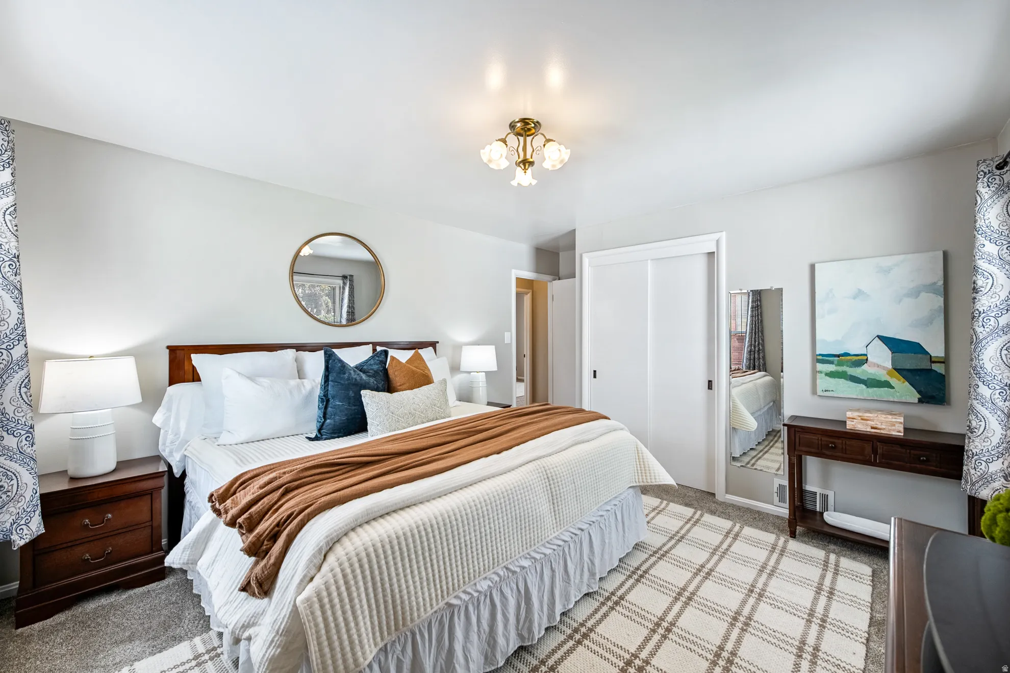 Recessed lighting, wood-finish nightstands, full-height sliding closet doors, and patterned area rug