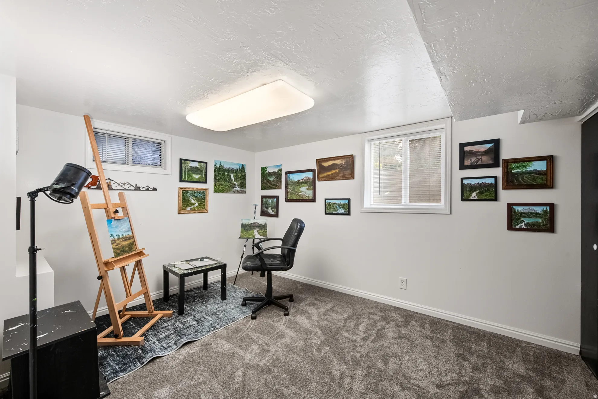 Versatile room featuring two windows with blinds, light gray wall paint, and gray carpet flooring