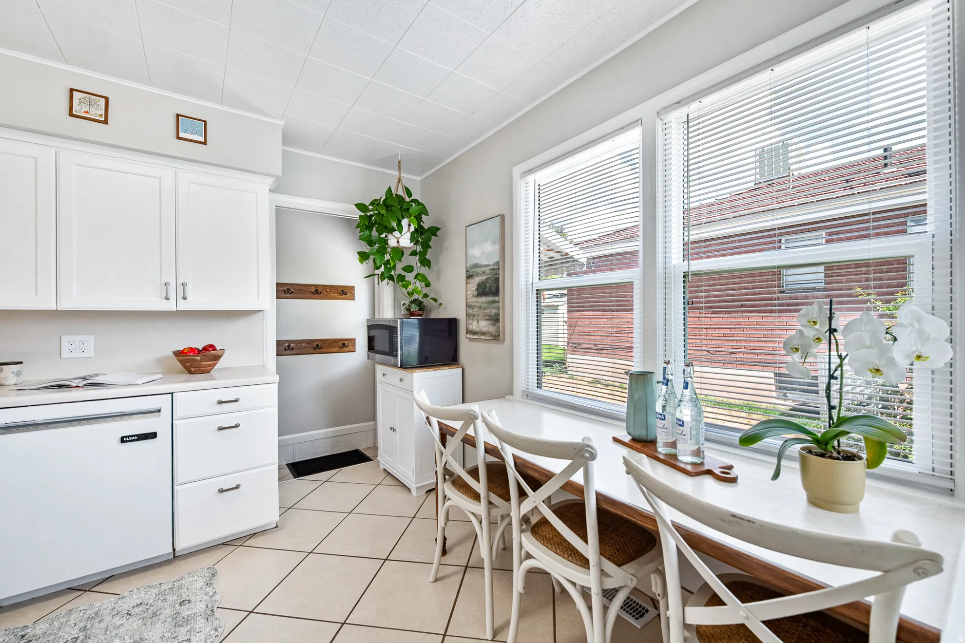 White cabinetry, white countertop, tile flooring, built-in window seating, and large windows with blinds