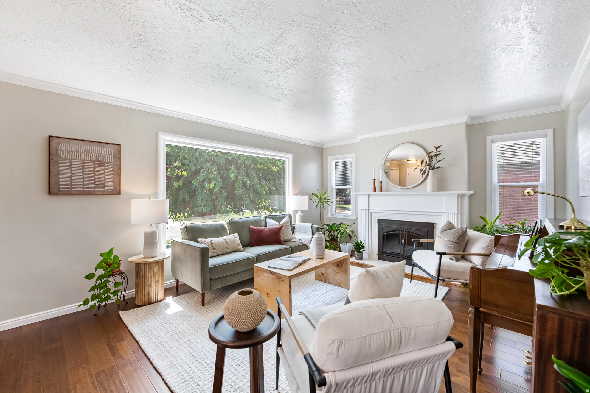 Hardwood-finish flooring, crown molding, a white mantel fireplace, and large windows