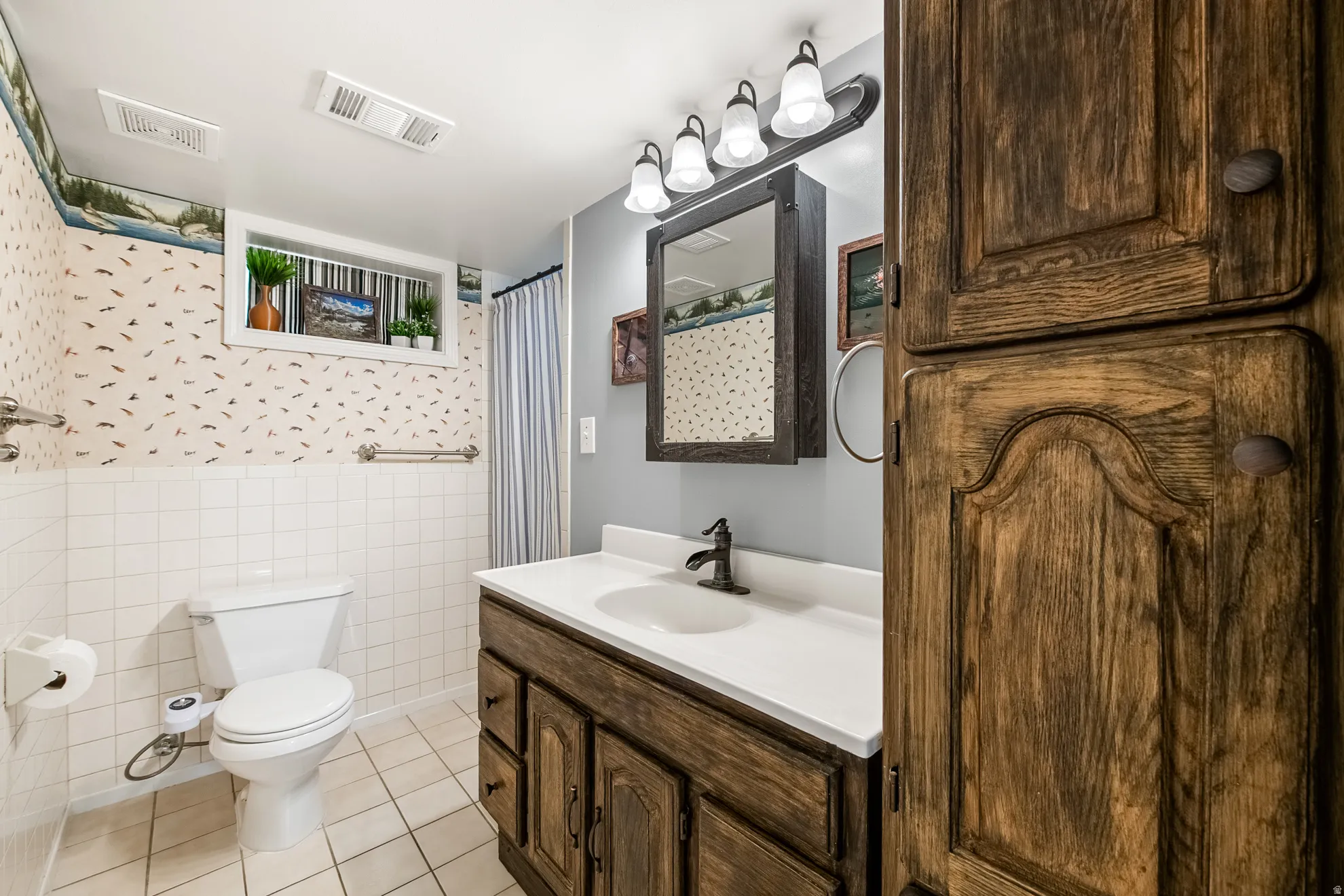 Bathroom featuring a wood-finish vanity with a white countertop and undermount sink, dark bronze-finish faucet, and a wall-mounted mirror